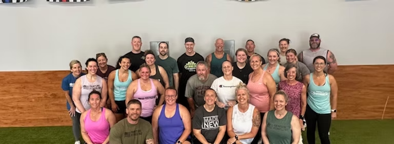 Frontline Fitness 302 members posing together for a group photo in the gym